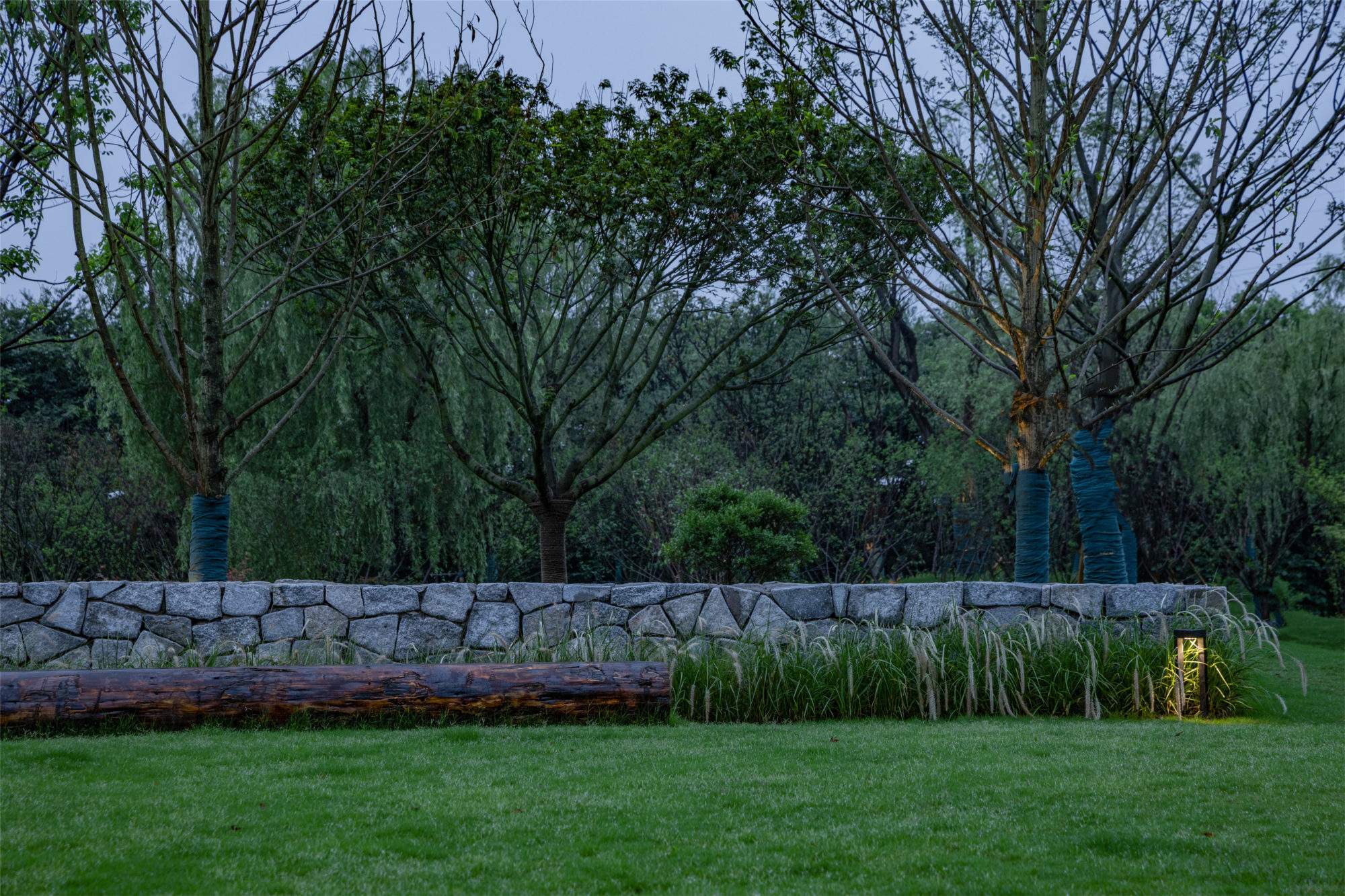 不刻意追求精致,仅用垒石矮墙,条形圆木,加以观赏草和景观灯点缀其中.